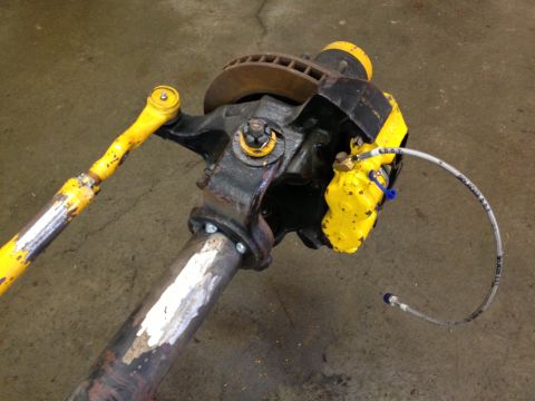 1988 Ford Bronco - Close-up of a vehicle's front axle assembly, showing the brake system and steering linkage.