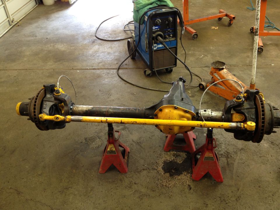 Front axle assembly with yellow tie rod, supported by red jack stands