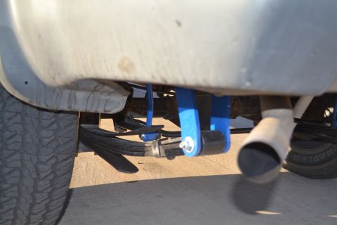 2004 Nissan Xterra - Close-up of the rear suspension components, including leaf springs and blue lift blocks, on a vehicle.