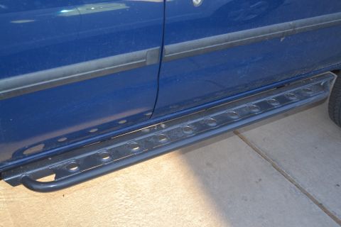 2004 Nissan Xterra - Close-up of the side of a blue SUV, highlighting its running boards and door trim.