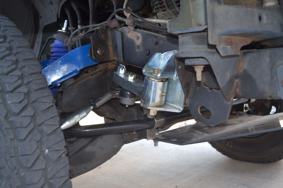 Close-up of modified suspension with blue control arms and silver bracketry