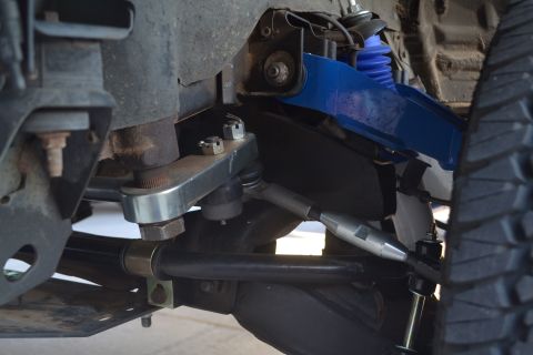 2004 Nissan Xterra - Detail view of aftermarket suspension parts, including a blue shock absorber and adjustable linkage, on an off-road vehicle.