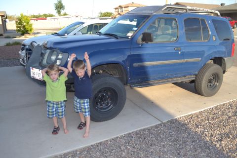 2004 Nissan Xterra - A blue 2004 Nissan Xterra is parked on a driveway with two excited children in front of it.