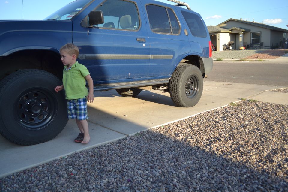 Blue 2004 Nissan Xterra with a child standing next to the front tire