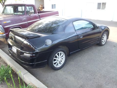 2001 Mitsubishi Eclipse - Black 2001 Mitsubishi Eclipse is parked next to an older model pickup truck.