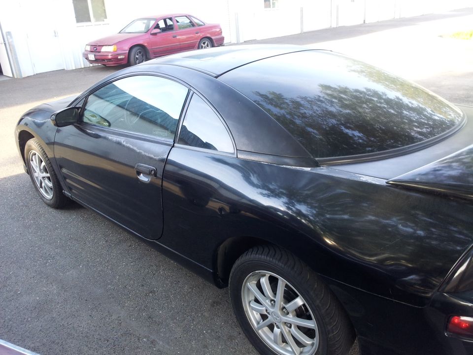 Black coupe, possibly a Mitsubishi Eclipse, parked next to a red sedan