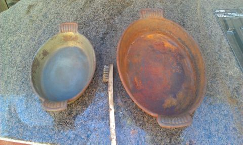 1989 Ford Bronco - Two rusty oval pans and a toothbrush are laid out on a textured surface, possibly for cleaning.