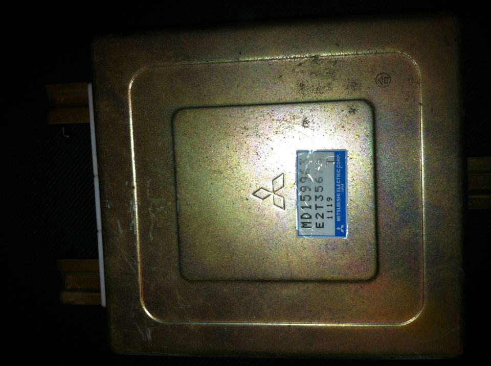 Gold engine control unit with a blue label showing Mitsubishi logo and part number MD159957 E2T356