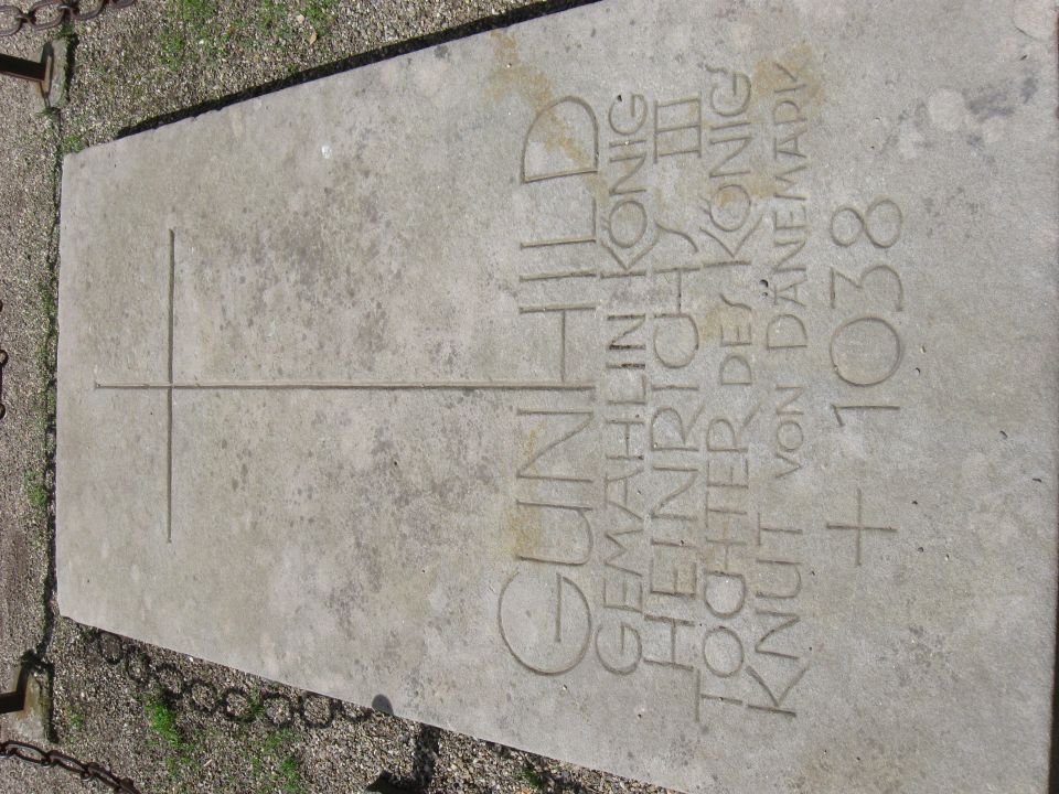 Gravestone with carved text and a cross, set in gravel with a chain border