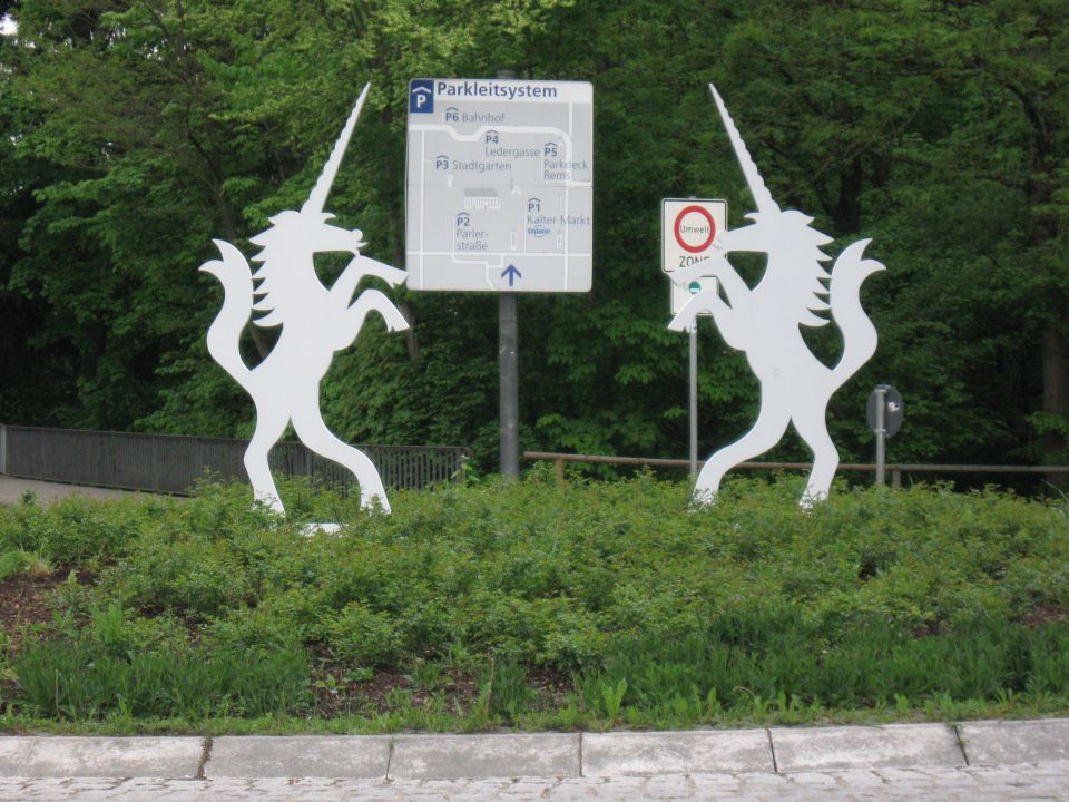 Two white unicorn statues flank a parking information sign