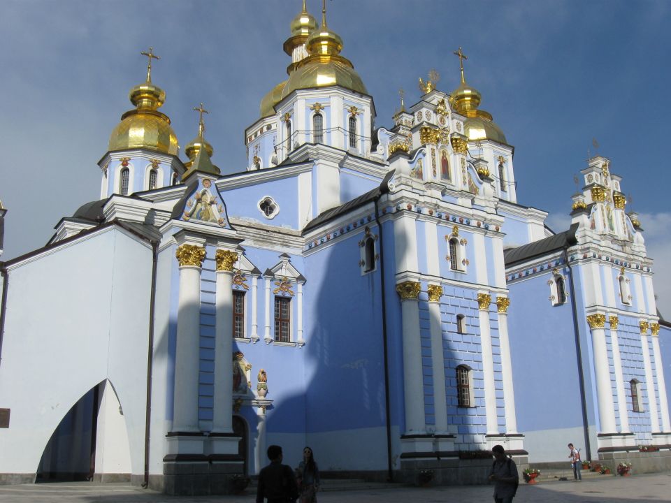 Blue and gold domed monastery with people in foreground
