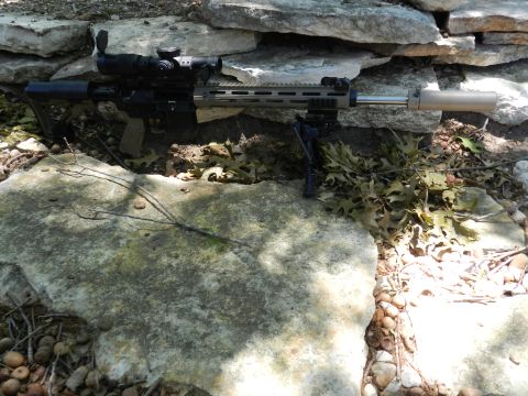 1996 Ford Bronco - A tactical rifle with accessories is positioned outdoors amongst natural elements.