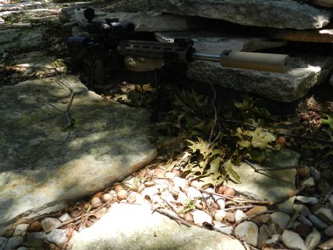 1996 Ford Bronco - A rifle with a scope and suppressor is partially visible amongst rocks and foliage.