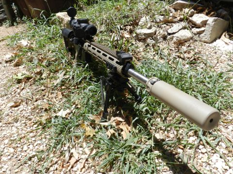 1996 Ford Bronco - A sniper rifle with a scope and suppressor is set up on a bipod in an outdoor grassy area.
