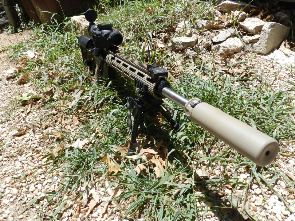 Sniper rifle with scope and suppressor on bipod, outdoors