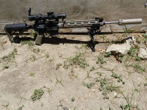 1996 Ford Bronco - Assault rifle with scope and bipod rests on the ground against a wooden wall.