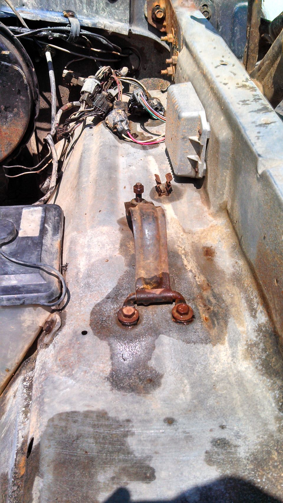 Rusty bracket and wiring harness in a vehicle's engine bay