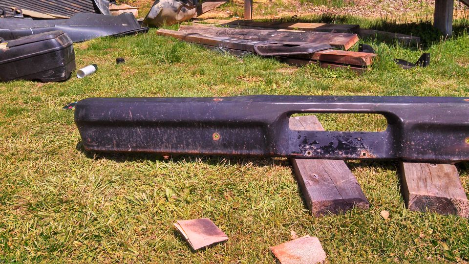 Black bumper with a large rectangular cutout, resting on wooden blocks on grass