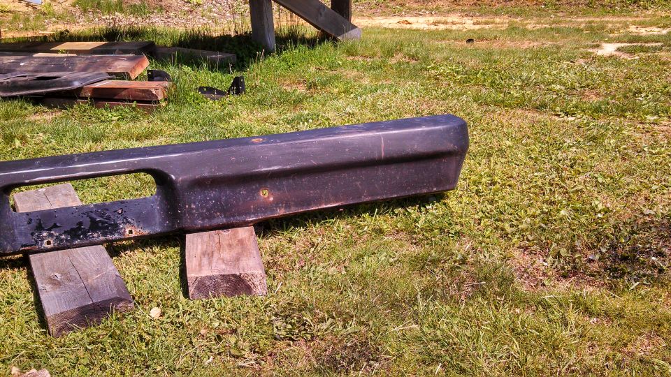 Dark front bumper with rectangular cutout, resting on wooden blocks
