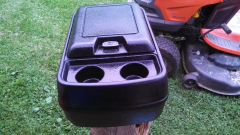 1979 Ford Bronco - A black aftermarket center console with cup holders is displayed outdoors.