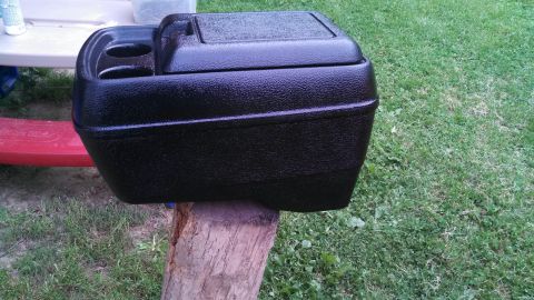 1979 Ford Bronco - Center console with cup holders and storage compartment sits on a log outdoors.