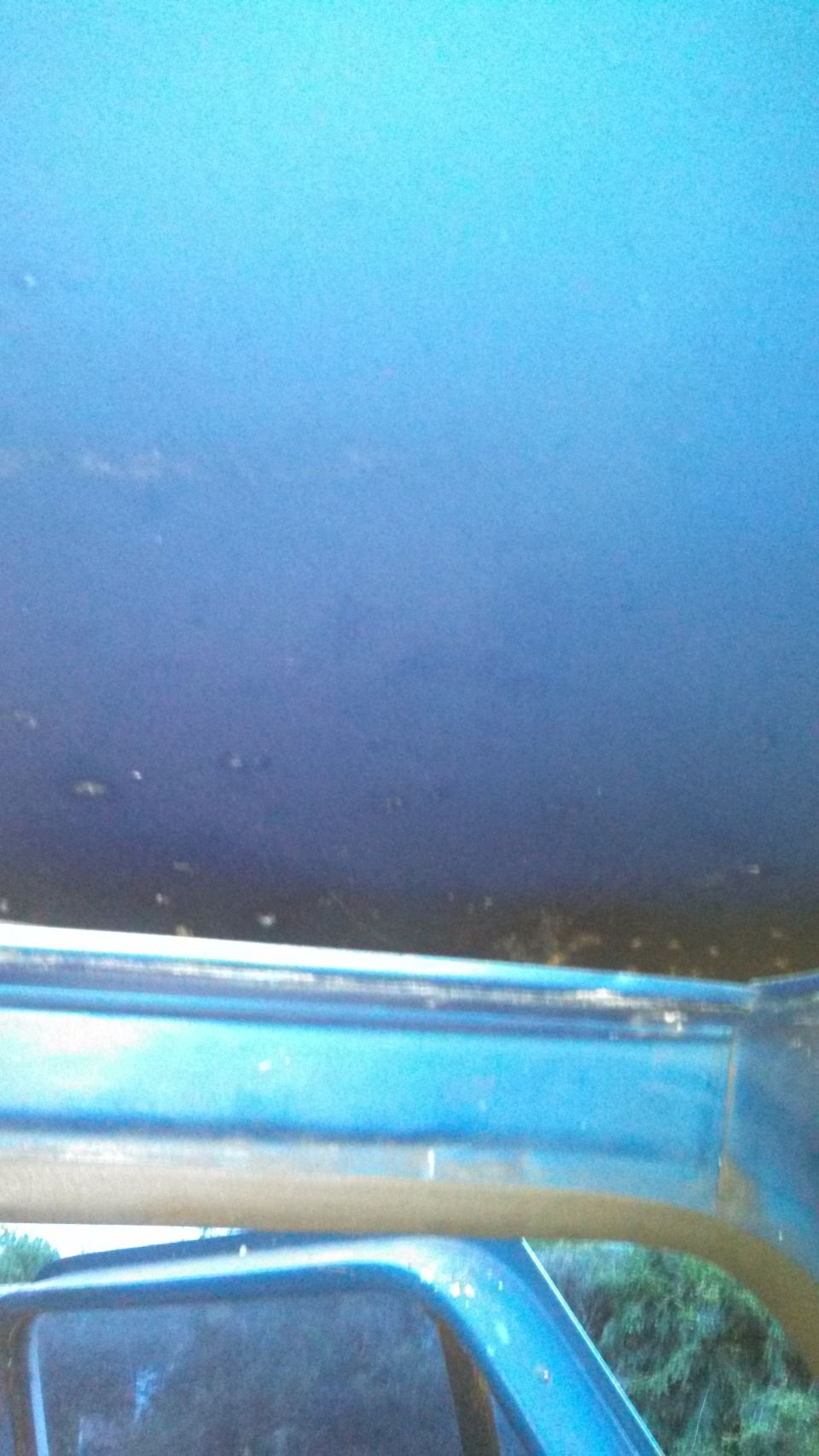 View of a blue vehicle's interior, looking up at the headliner and down at the side window frame. Watermark visible