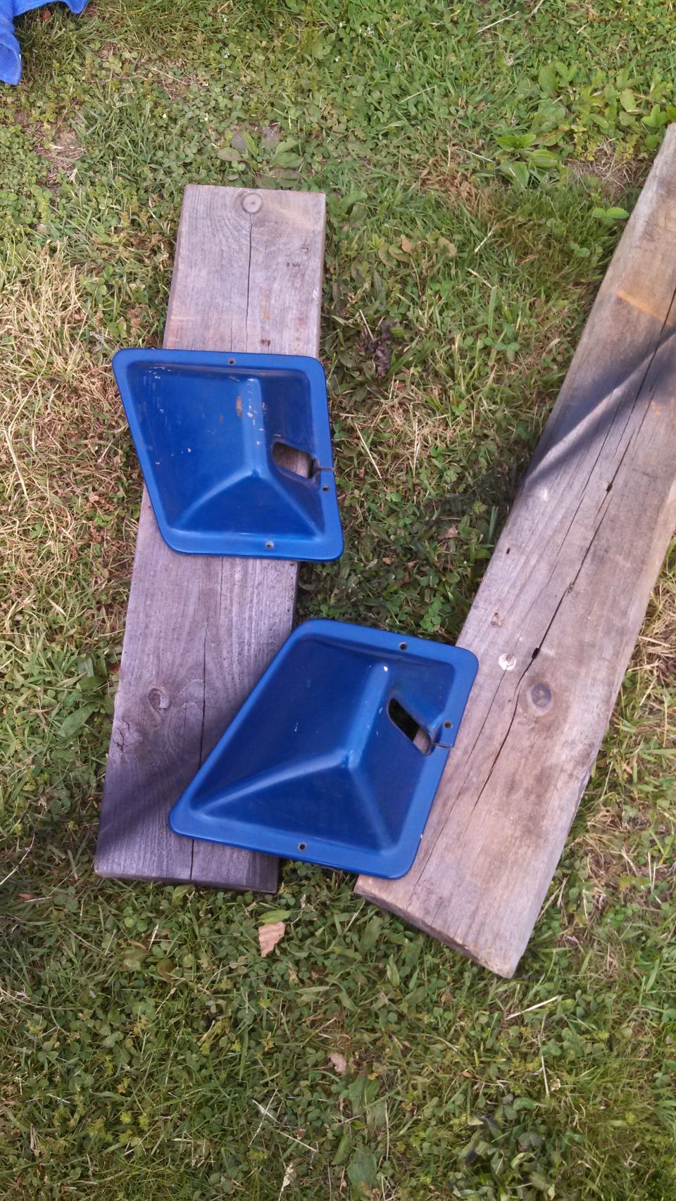 Two blue plastic door panels resting on wooden planks on grass