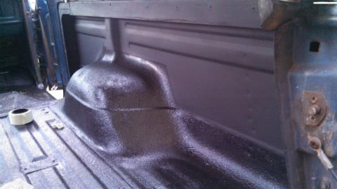 1979 Ford Bronco - The interior of a truck bed, likely undergoing a spray-on liner application, shows the textured surface and a roll of tape.
