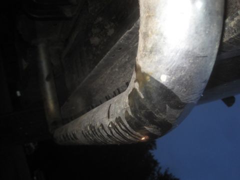 1993 Ford Bronco - Close-up view of a vehicle's exhaust pipe, showing water dripping from its surface.