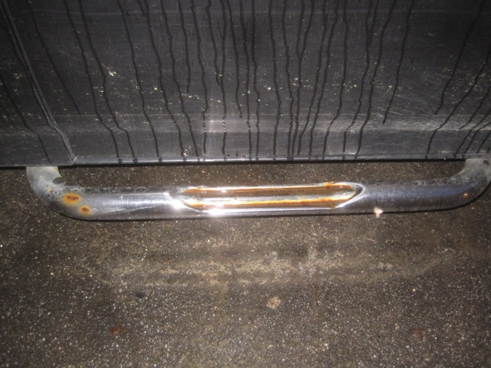 Rusted chrome step bar attached to the side of a vehicle