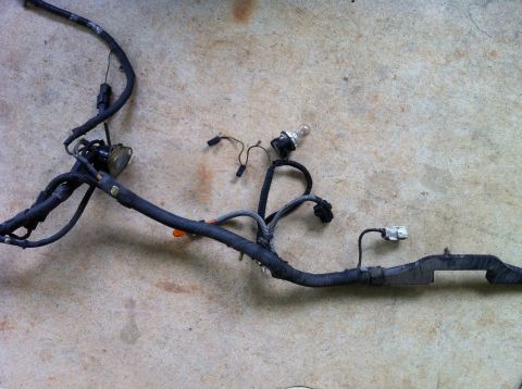 1992 Ford Bronco - A vehicle wiring harness is laid out on a concrete surface, showing various connectors and a single light bulb.