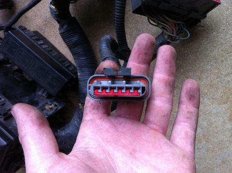 1992 Ford Bronco - A hand holds a wiring harness connector, part of a vehicle's electrical system.