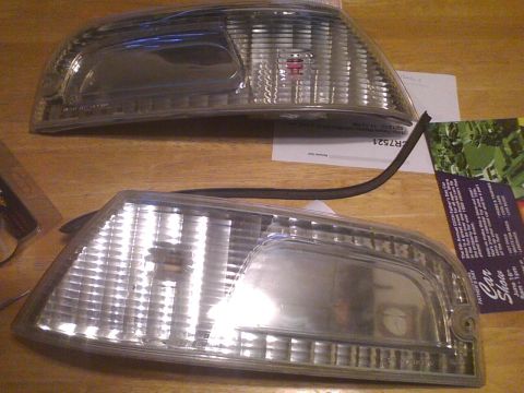 2003 Ford Crown Victoria - Two clear plastic car headlights are shown on a wooden table with some papers and a flyer.