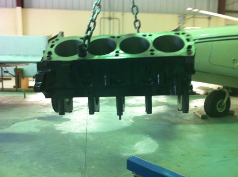 1992 Ford Bronco - An engine block is being hoisted in a workshop, with a green airplane visible in the background.