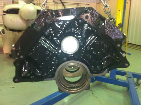 1992 Ford Bronco - Engine block with oil residue, suspended by chains over a blue stand.