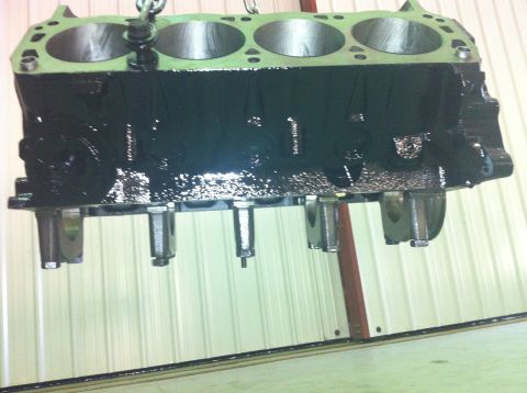 1992 Ford Bronco - A black engine block, likely for a Ford vehicle, is shown suspended by a chain, ready for assembly or inspection.
