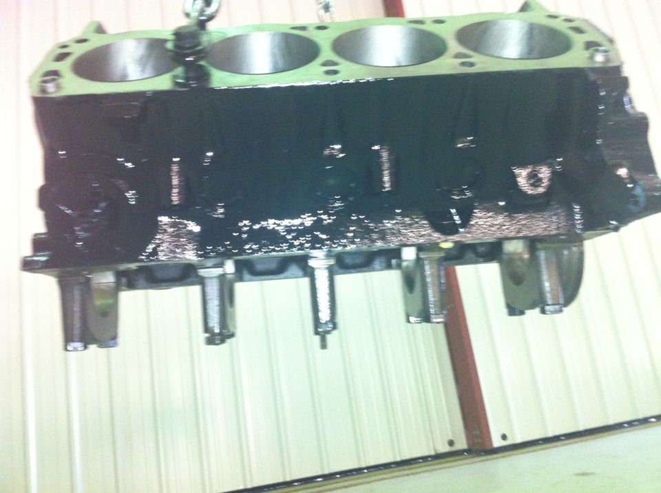 Black engine block with four cylinders, suspended by a chain