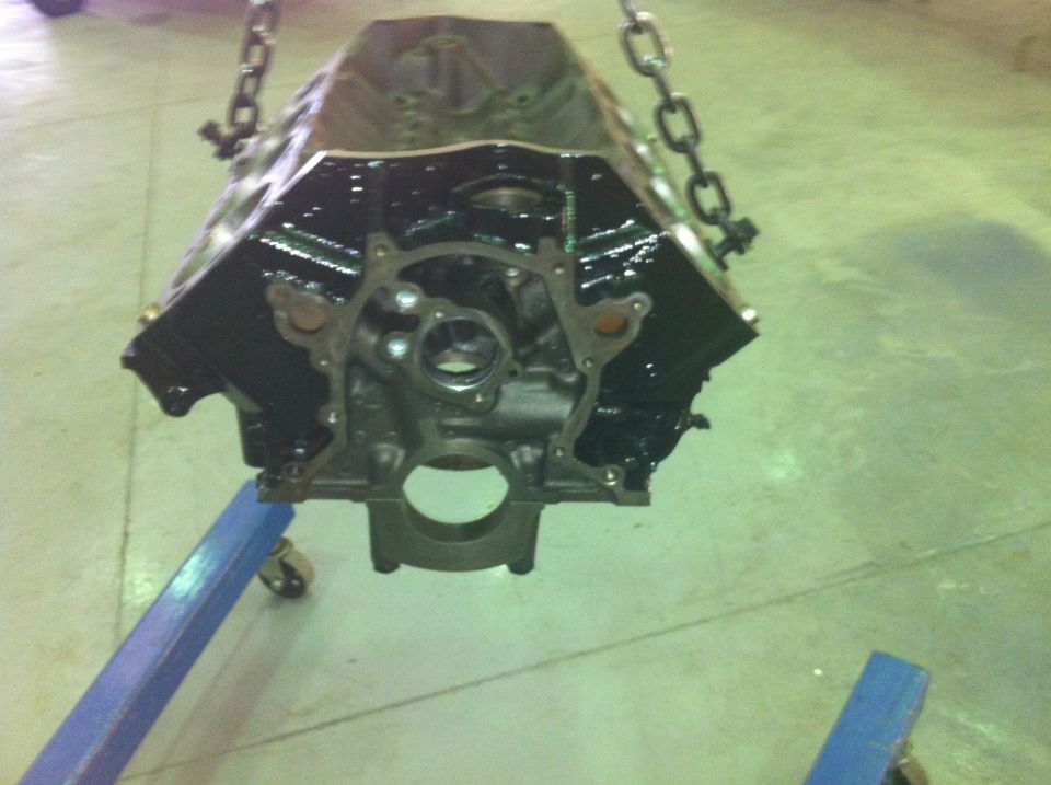Black engine block suspended by chains, supported by a blue engine stand