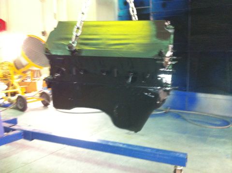 1992 Ford Bronco - Engine block is being painted green and black while suspended by chains in a workshop.
