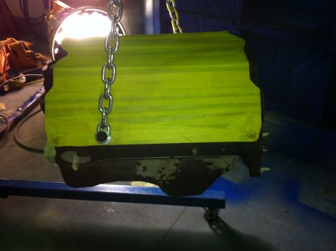 1992 Ford Bronco - Engine block covered in yellow tape, suspended by chains, with a bright light in the background.