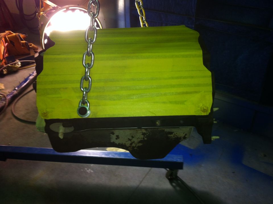 Engine block covered in yellow tape, suspended by chains