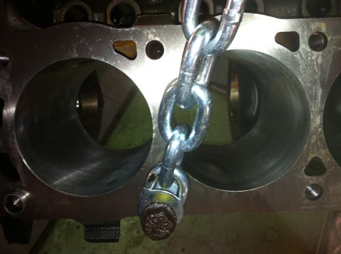 1992 Ford Bronco - Close-up view of an engine block's cylinders with a heavy-duty metal chain obscuring part of the view.