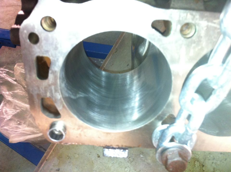 Engine cylinder block with visible honing marks inside the cylinder bore and a metal chain attached