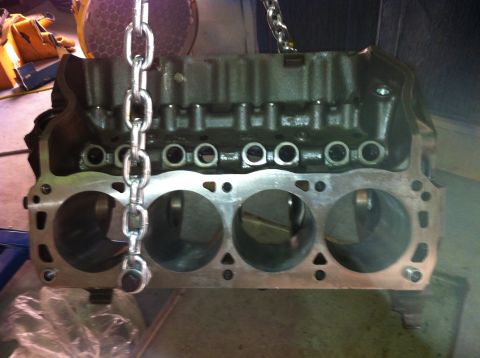 1992 Ford Bronco - This is a close-up view of an engine block, suspended by a chain hoist, revealing its internal cylinder structure.