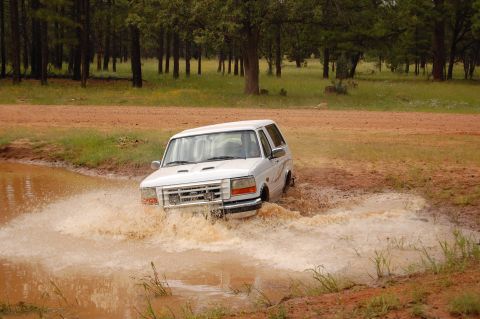 1996 Ford Bronco - 1996 Ford Bronco navigates a challenging muddy water crossing.