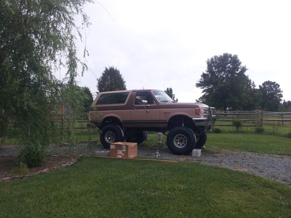 Lifted brown 1988 Ford Bronco with tan top, side view