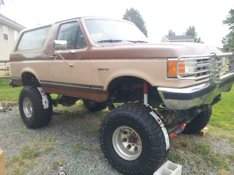 1988 Ford Bronco - This lifted Ford Bronco features a two-tone paint scheme and is equipped with large off-road tires.