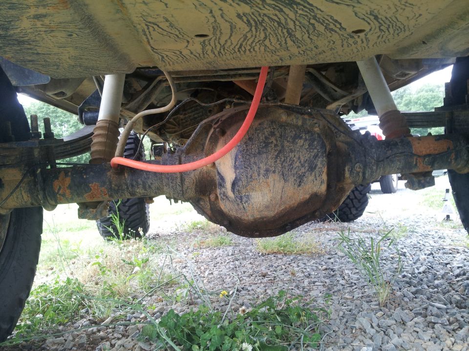 Rear axle assembly with orange hose and leaf springs, viewed from underneath