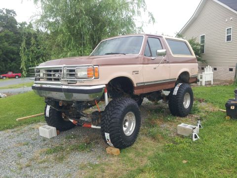 1988 Ford Bronco - This lifted SUV features a two-tone brown and tan paint scheme and massive off-road tires.