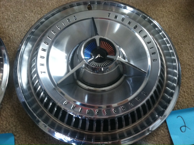 Chrome hubcap with 'THUNDERBIRD' text and a central emblem with blue and orange fins